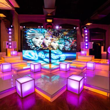 A vibrant stage setup in NY features illuminated white steps, glowing cube seats, colorful abstract face art on a digital screen, and large "LOVE" letters lit up—perfect for entertainment services Suffolk and Nassau County.