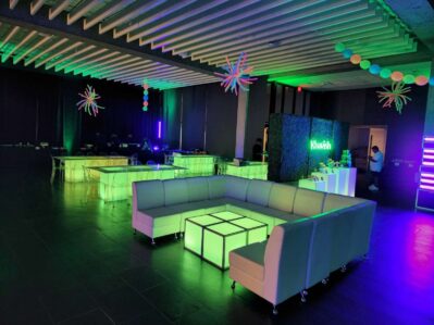 A modern lounge in NY,NY with glowing green and white LED furniture—including sofas and tables—plus colorful hanging decorations, a “Klash” sign, and dim accent lighting in green and purple. Perfect for DJ services Suffolk and Nassau County.